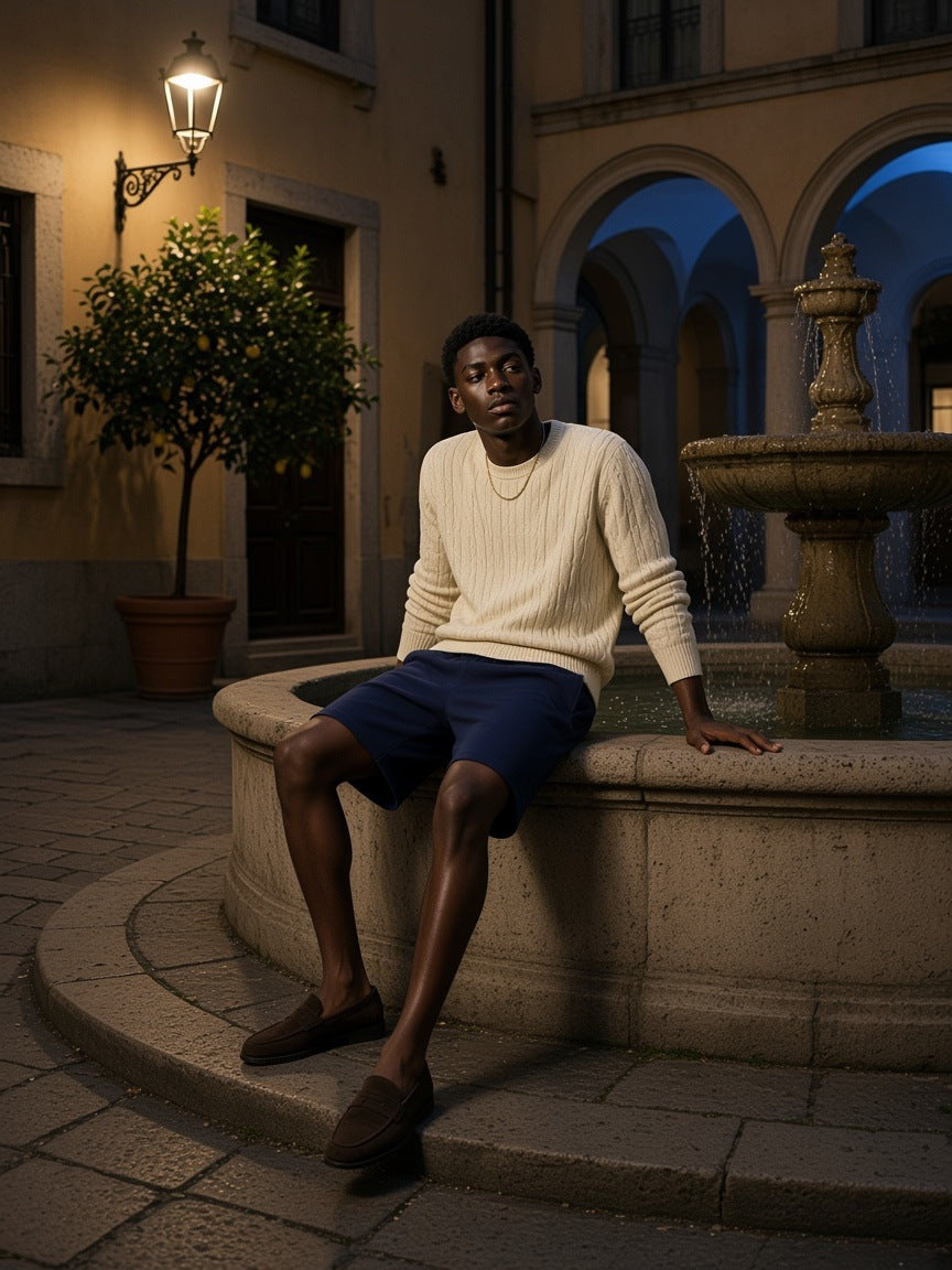 Man in the Essential Heavyweight Cotton Shorts in Navy Blue seated on a fountain rim in a Milan palazzo courtyard at night