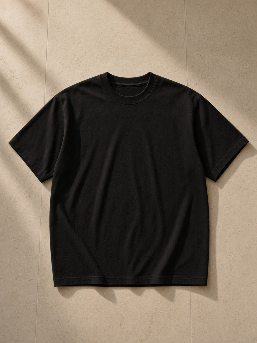 Essential Heavyweight Cotton T-Shirt in Black, laid flat on pale limestone