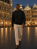 Marcel Afters Essential Heavyweight Crewneck Sweatshirt — Dark in Black, worn by a man, walking across a lit Brussels square at night