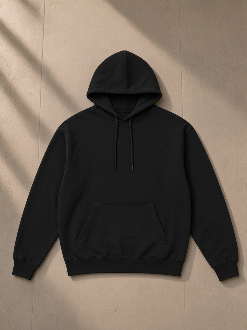Unisex heavyweight hoodie in Black, laid flat on pale limestone, front view