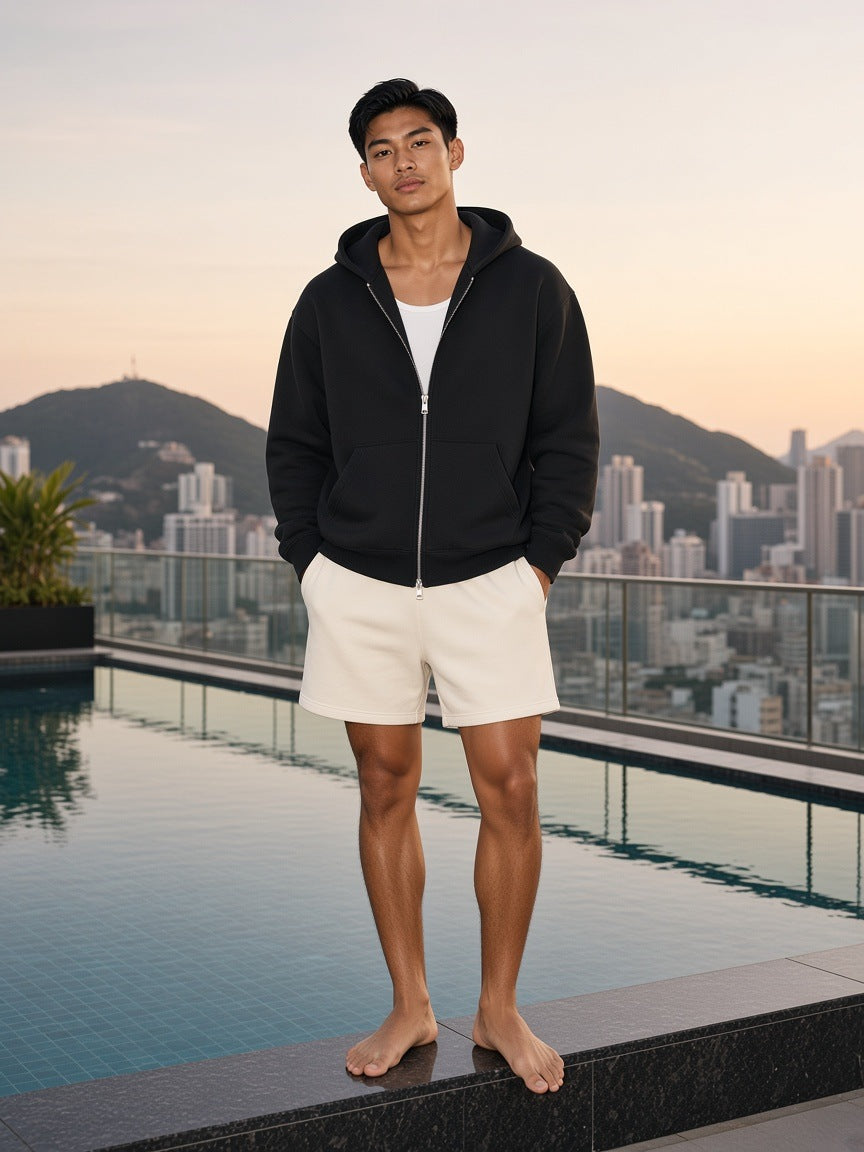 Marcel Afters Essential Heavyweight Pocket Hoodie in Black, worn by a man, city rooftop at dusk