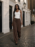 Marcel Afters Fleece Drawstring Straight-Leg Sweatpants in Brown, worn by a woman, cobbled street