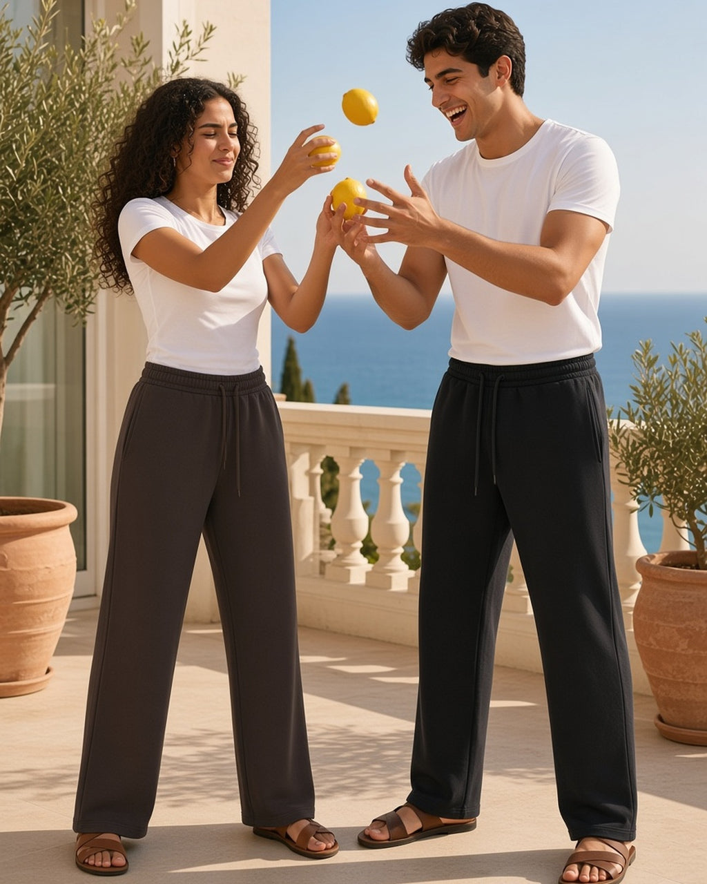 Two people in the Fleece Drawstring Straight-Leg Sweatpants in Brown and Black juggling lemons on a Riviera terrace