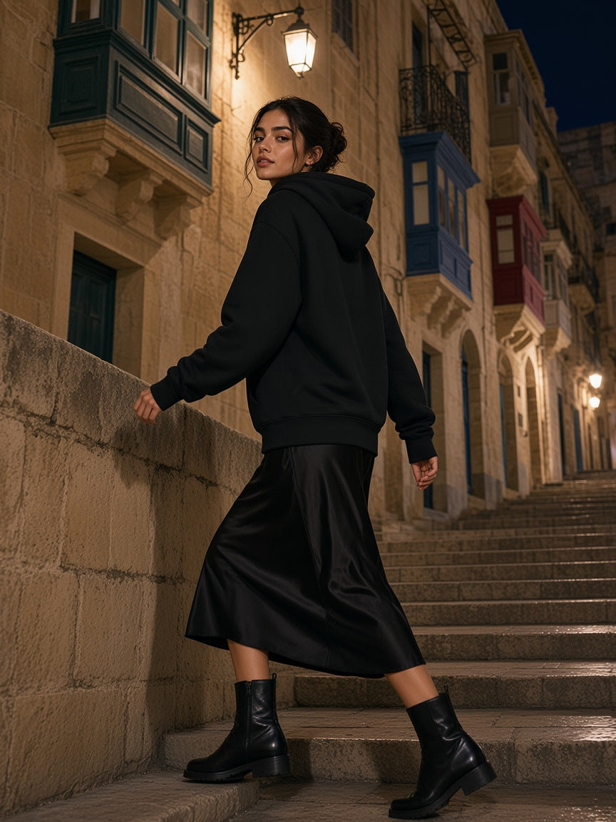 Marcel Afters Fleece Regular Shoulder Hoodie in Black, worn by a woman, walking up old stone steps at night in a black skirt
