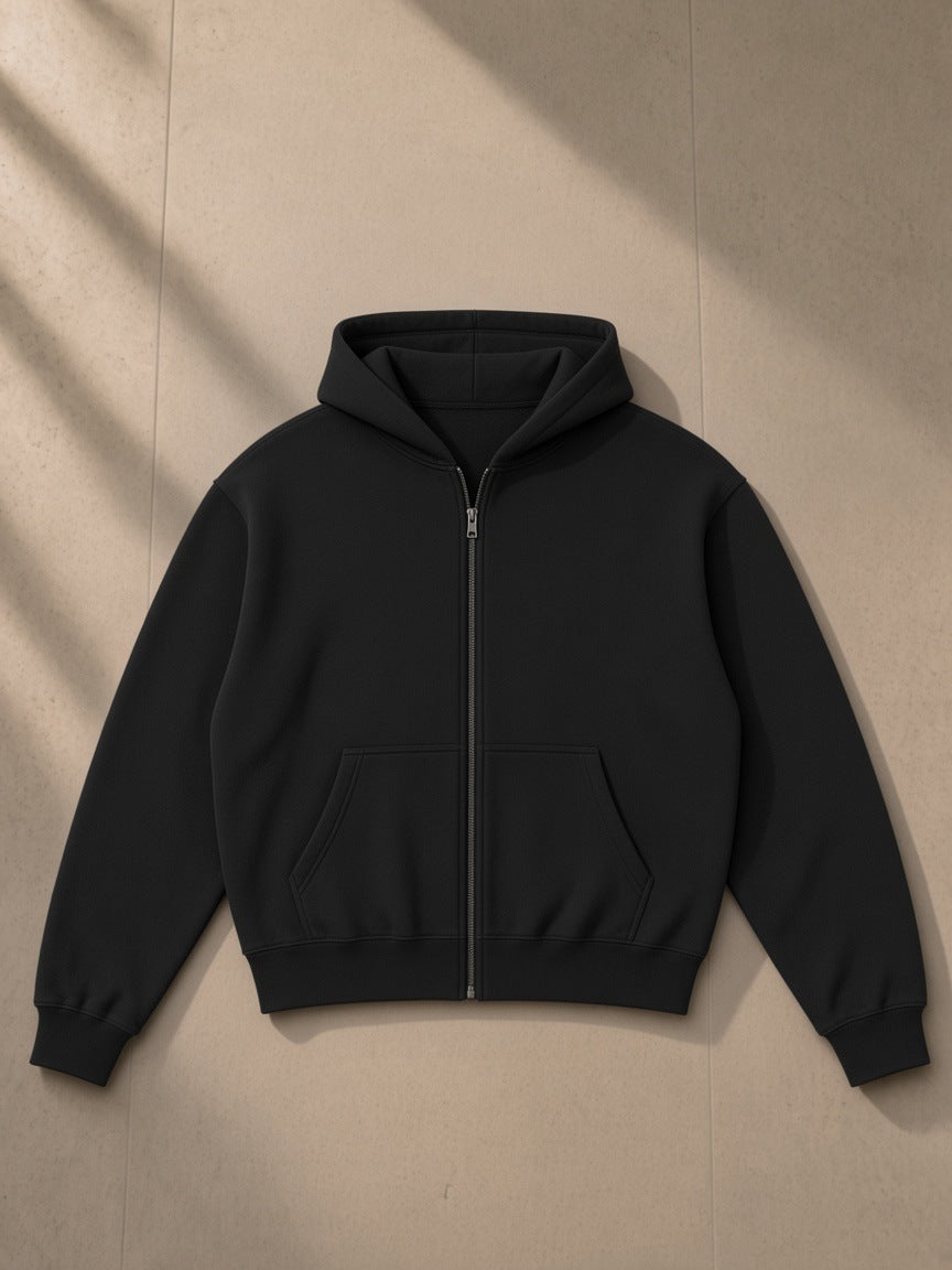 Unisex fleece zip-up boxy hoodie in Black, laid flat on pale limestone, front view
