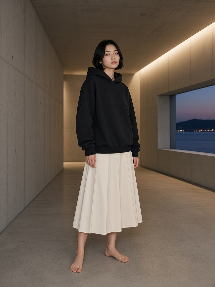 Marcel Afters Fleeced Boxy Hoodie in Black, worn by a woman, concrete hallway