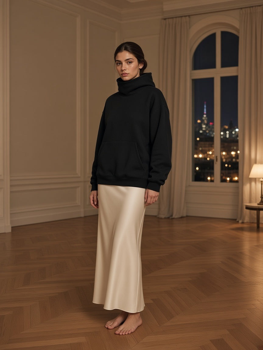 Marcel Afters Fleeced High Neck Hoodie in Black, worn by a woman, wooden floor