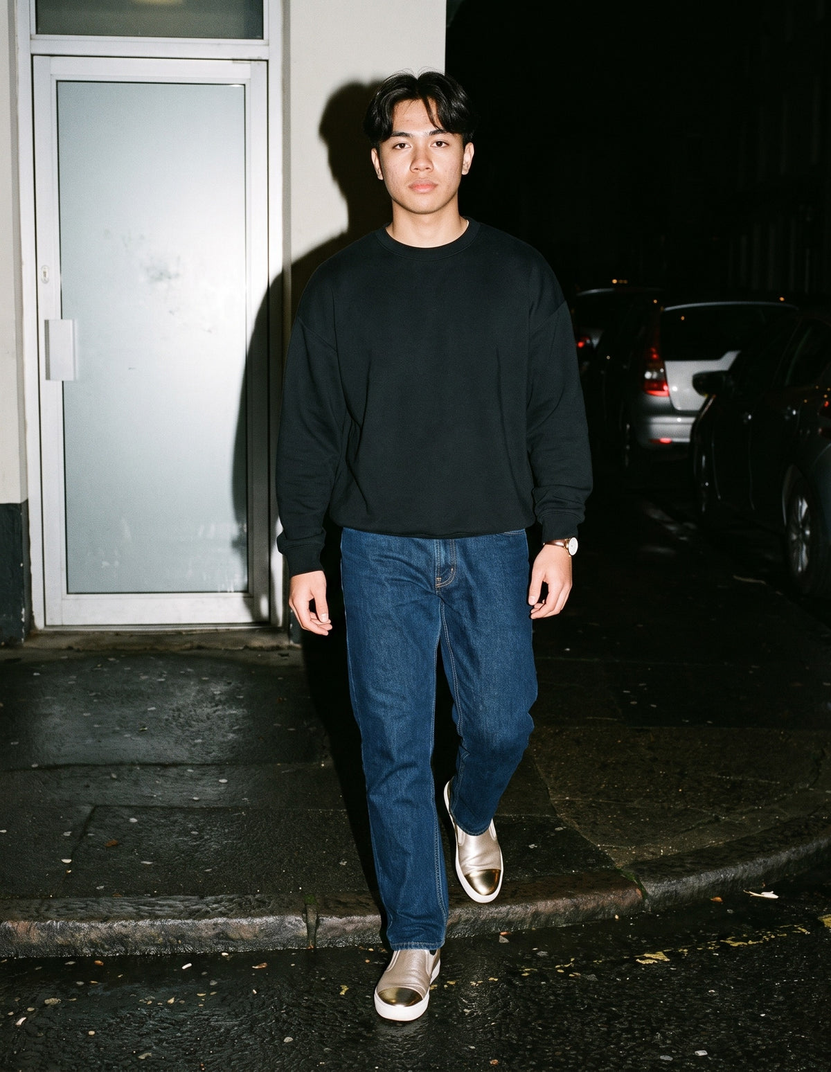 Man wearing The Champagne Slip-On with the Oversized Drop Shoulder Crewneck Sweatshirt in Black, Heavyweight Straight-Leg Denim Jeans in Navy Blue. After Dark, Autumn–Winter 2026 campaign