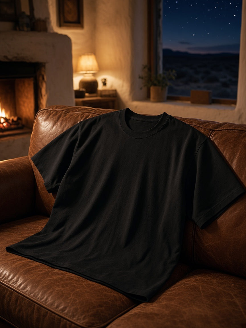 Marcel Afters Heavyweight Drop Shoulder Cotton T-Shirt in Classic Black, laid flat, living room