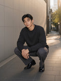 Man in the Heavyweight Drop Shoulder Sweatshirt in Black Beauty with charcoal trousers and loafers, in a stone alley in Aoyama, Tokyo in the morning