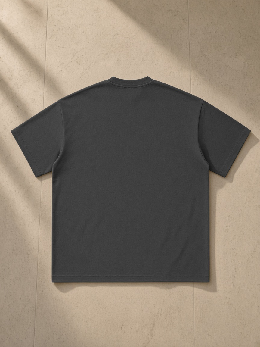 Heavyweight Earth Tone T-Shirt in Carbon Gray, laid flat on pale limestone, back.