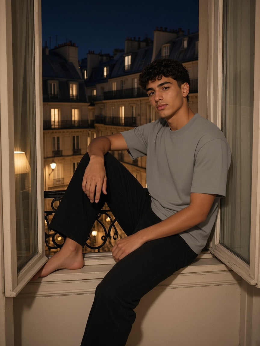 Marcel Afters Heavyweight Earth Tone T-Shirt in Gray Camel, worn by a man, seated in a Paris window at night