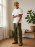 Man in the Heavyweight Earth Tone T-Shirt in White by the window of a pale timber Copenhagen apartment