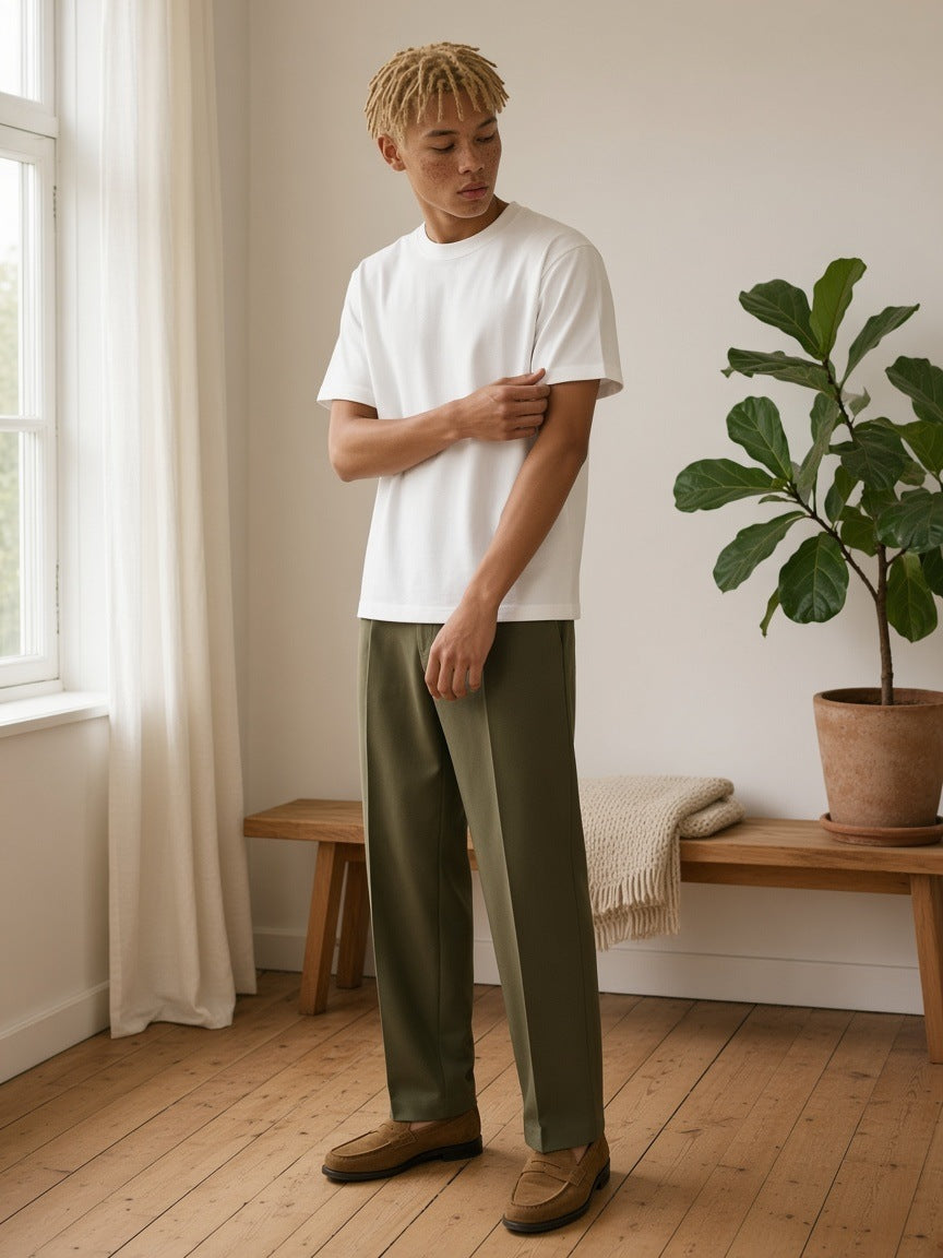 Man in the Heavyweight Earth Tone T-Shirt in White by the window of a pale timber Copenhagen apartment
