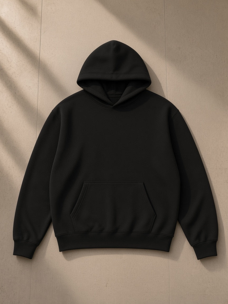 Unisex heavyweight fleece boxy hoodie in Black, laid flat on pale limestone, front view