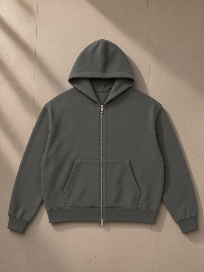 Heavyweight boxy full-zip hoodie in Dark Gray, laid flat on pale limestone, front view