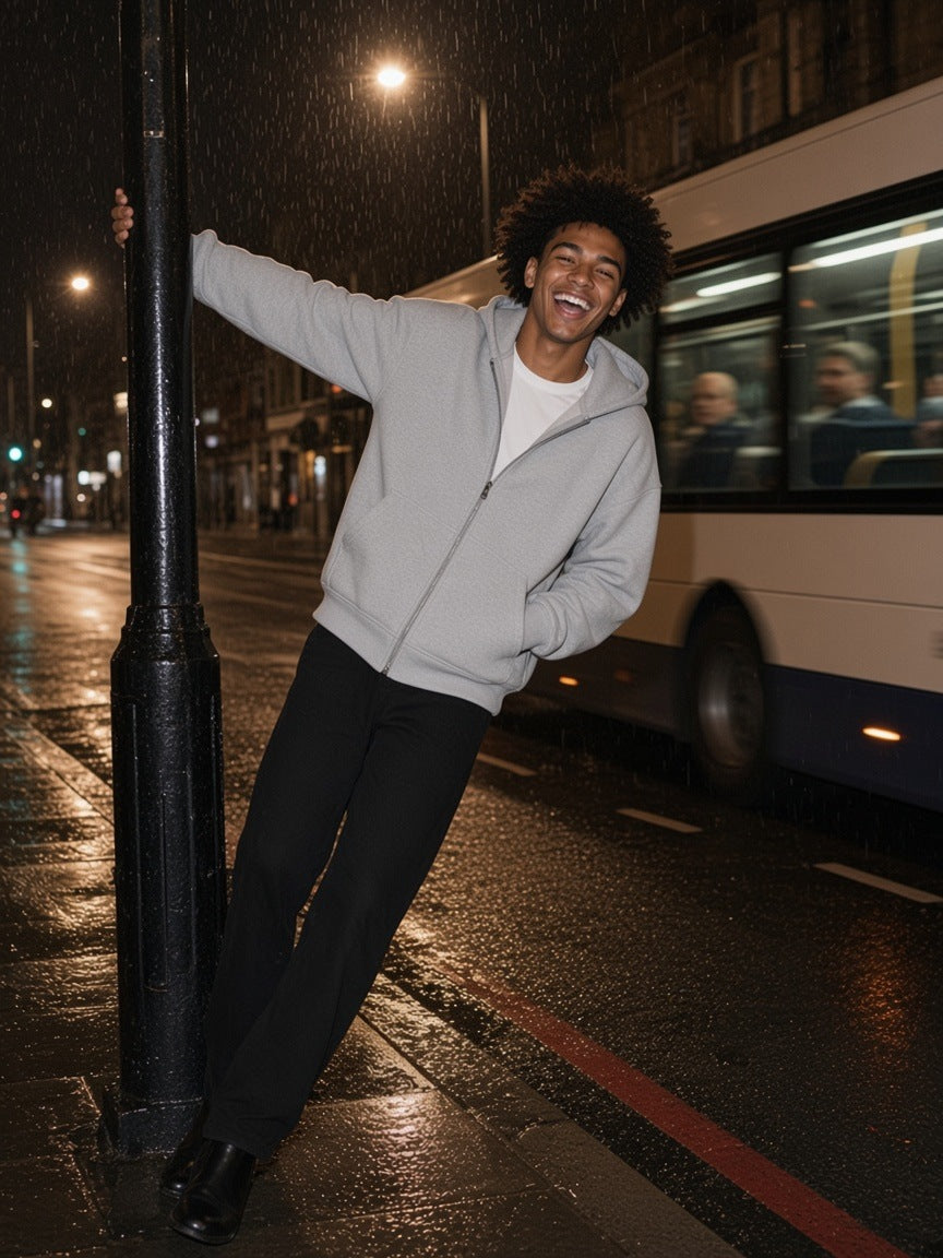 Man in the Heavyweight Full Zip Boxy Hoodie in Flower Gray, swinging off a lamppost by a London night bus at 4am
