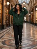 Woman in the Heavyweight Full Zip Hoodie in Blackish Green walking through a covered Paris passage in the evening