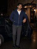 Man in a Navy Blue heavyweight full zip hoodie beside a car outside a grand hotel at night