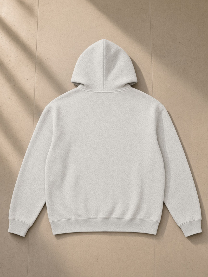 Heavyweight full-zip hoodie in Oat Gray, laid flat on pale limestone, back view