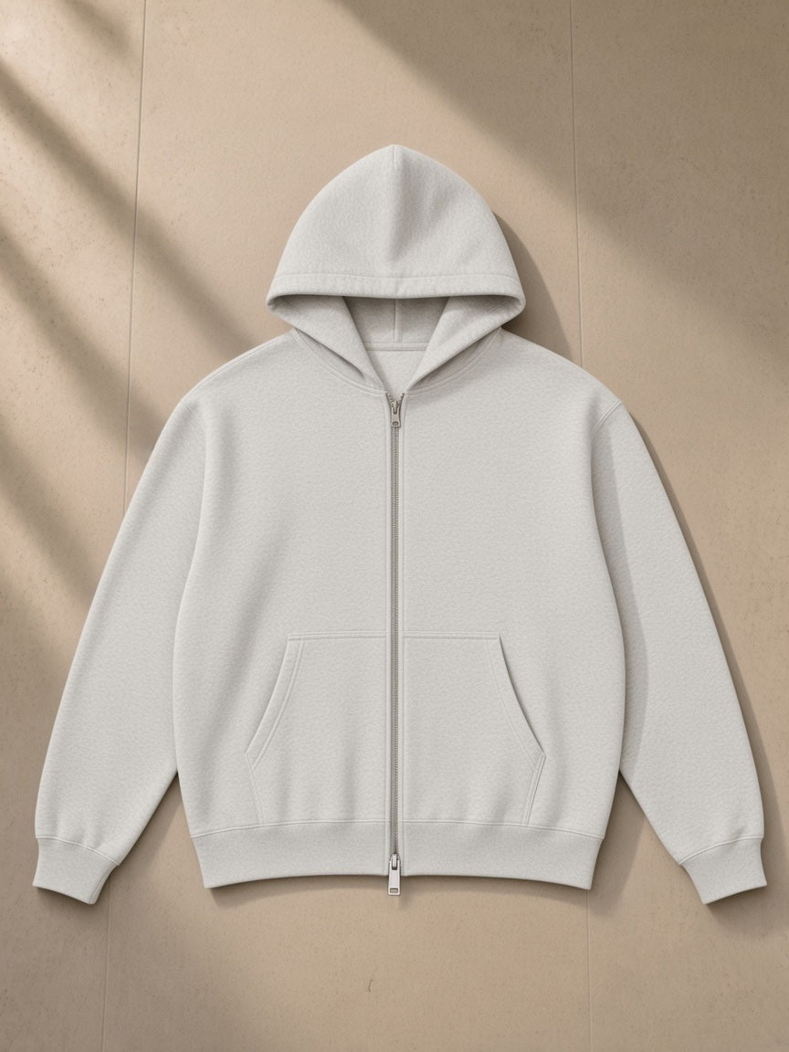 Heavyweight full-zip hoodie in Oat Gray, laid flat on pale limestone, front view