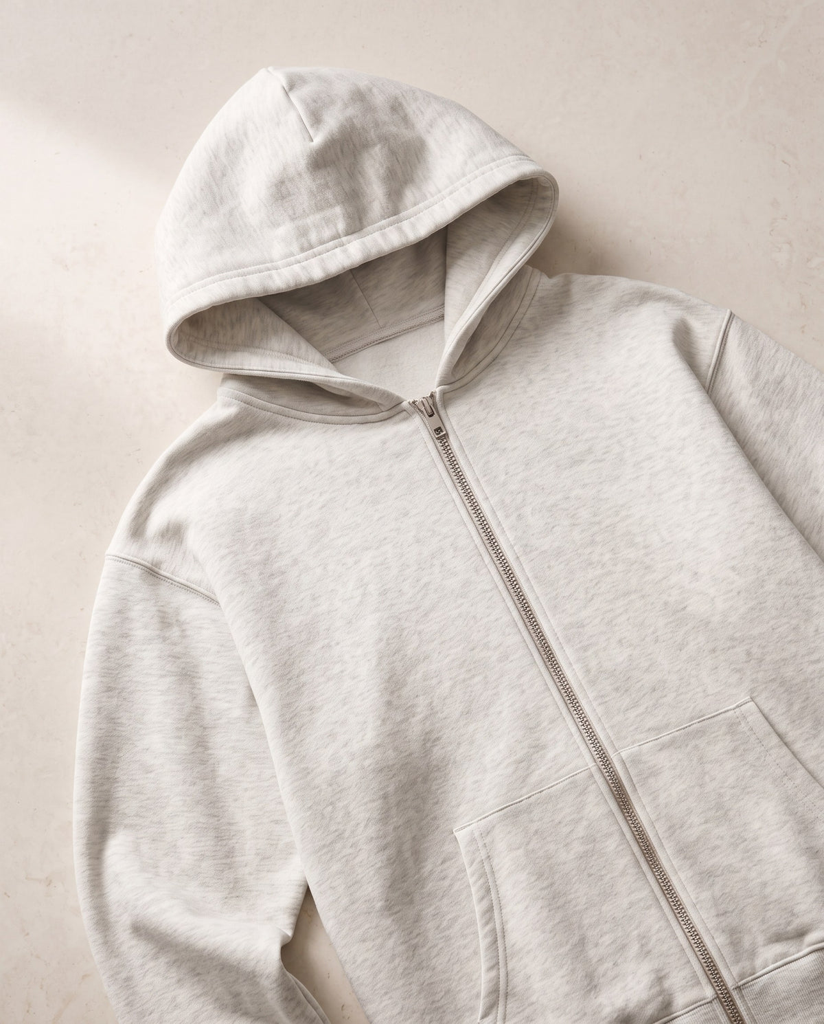Close-up of the hood, drop shoulder seam and silver zip on the Heavyweight Full Zip Hoodie in Oat Gray