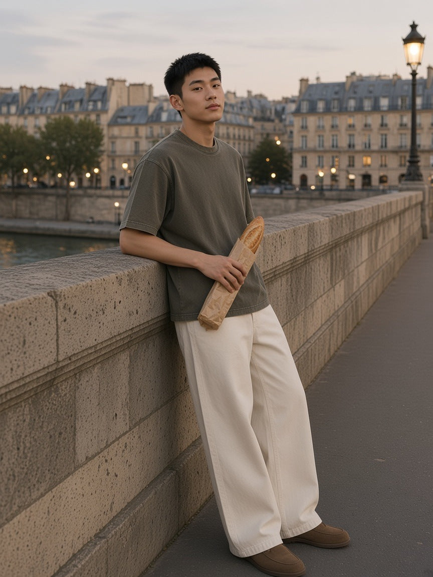 Man in the Heavyweight Mineral Wash Boxy T-Shirt in Brown leaning on a Seine bridge parapet at blue hour