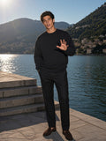 Marcel Afters Heavyweight Oversized Boxy Sweatshirt in Black, worn by a man, standing on lakeside stone steps in the afternoon sun