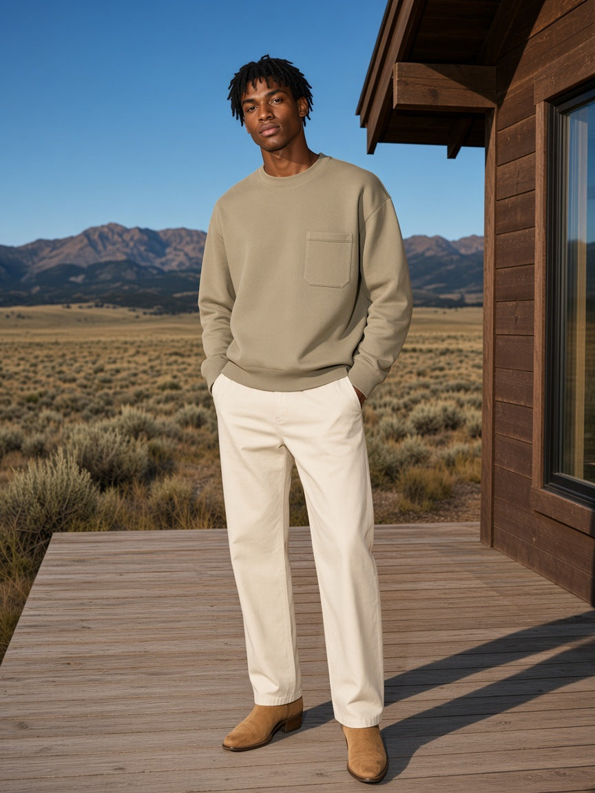 Marcel Afters Heavyweight Patch Pocket Crewneck Sweatshirt in Khaki, worn by a man, standing on a timber porch in front of open prairie