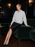 Marcel Afters Heavyweight Polo-Collar Sweatshirt in light grey, worn with a black satin skirt on a velvet banquette