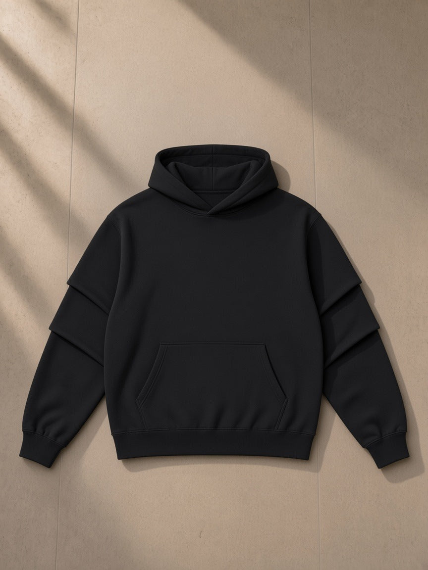 Unisex heavyweight ruched sleeves hoodie in Black, laid flat on pale limestone, front view