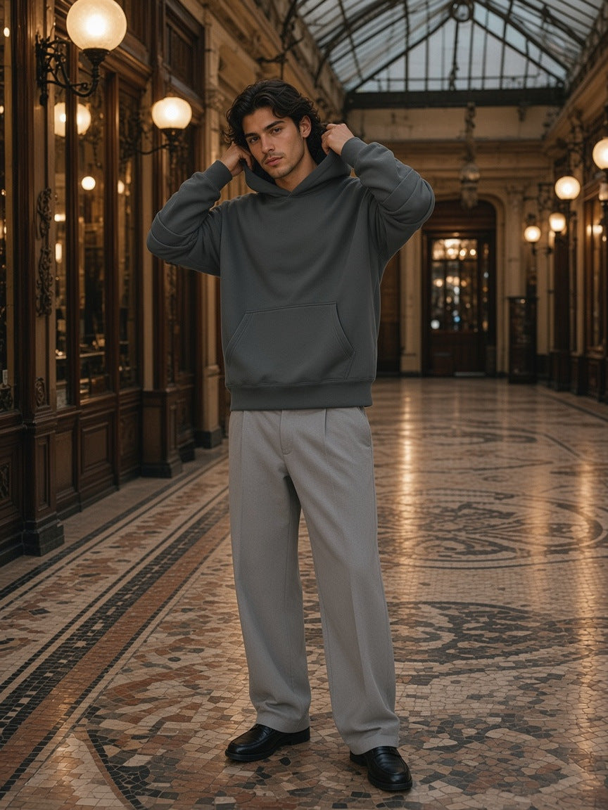 Marcel Afters Heavyweight Ruched Sleeves Hoodie in Dark Gray, worn by a man, standing in a gaslit Paris arcade with his hood up