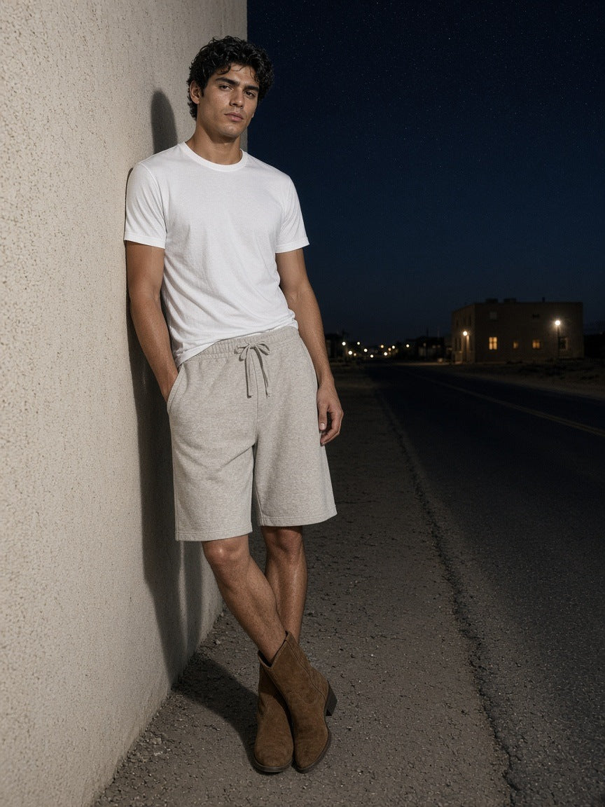Man in the Heavyweight Shorts in Oat Gray leaning on an adobe wall in Marfa, Texas at night