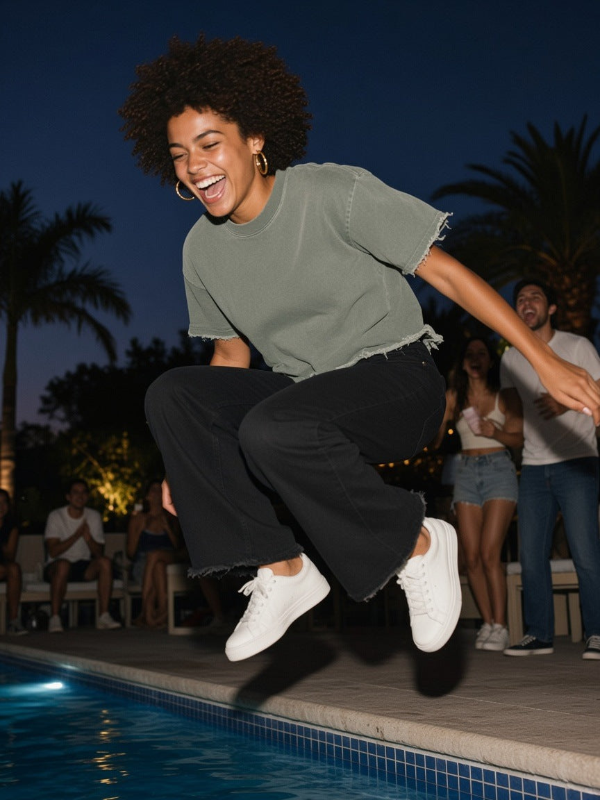 Woman in the Heavyweight Vintage Washed Frayed T-Shirt in Gray Green, jumping into a Mexico City hotel pool at midnight