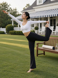 Woman in the Women's High-Waisted Flare Leggings in Black holding a dancer's pose on the clubhouse lawn at a country club