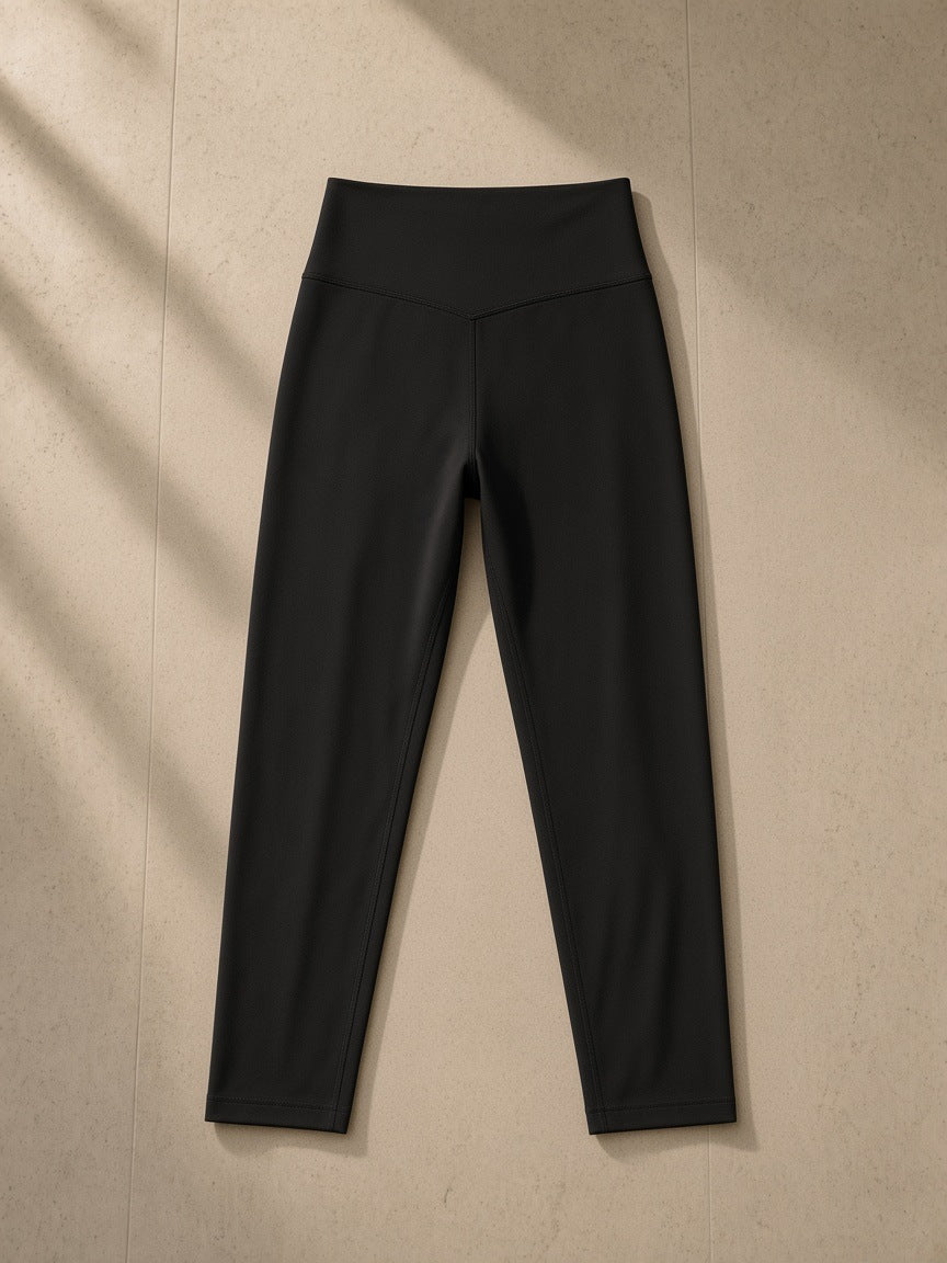 High-Waisted Yoga Leggings in Black, laid flat on pale limestone, back view