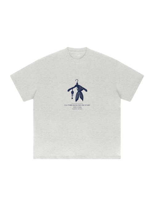 I'll Come Back For The Scarf heavyweight tee in Oat Gray, front view with a hanger, silk scarf and hotel key for New York. Marcel Afters.