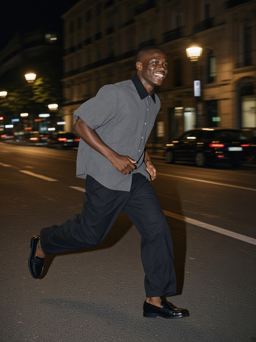 Part of the look Wrong Party: man in a dark gray striped boxy contrast-collar shirt and black barrel dress pants