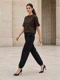 Woman in the Loose Fit Tapered Joggers in Black with a Coffee boxy tee striding across a limestone Paris courtyard in heels