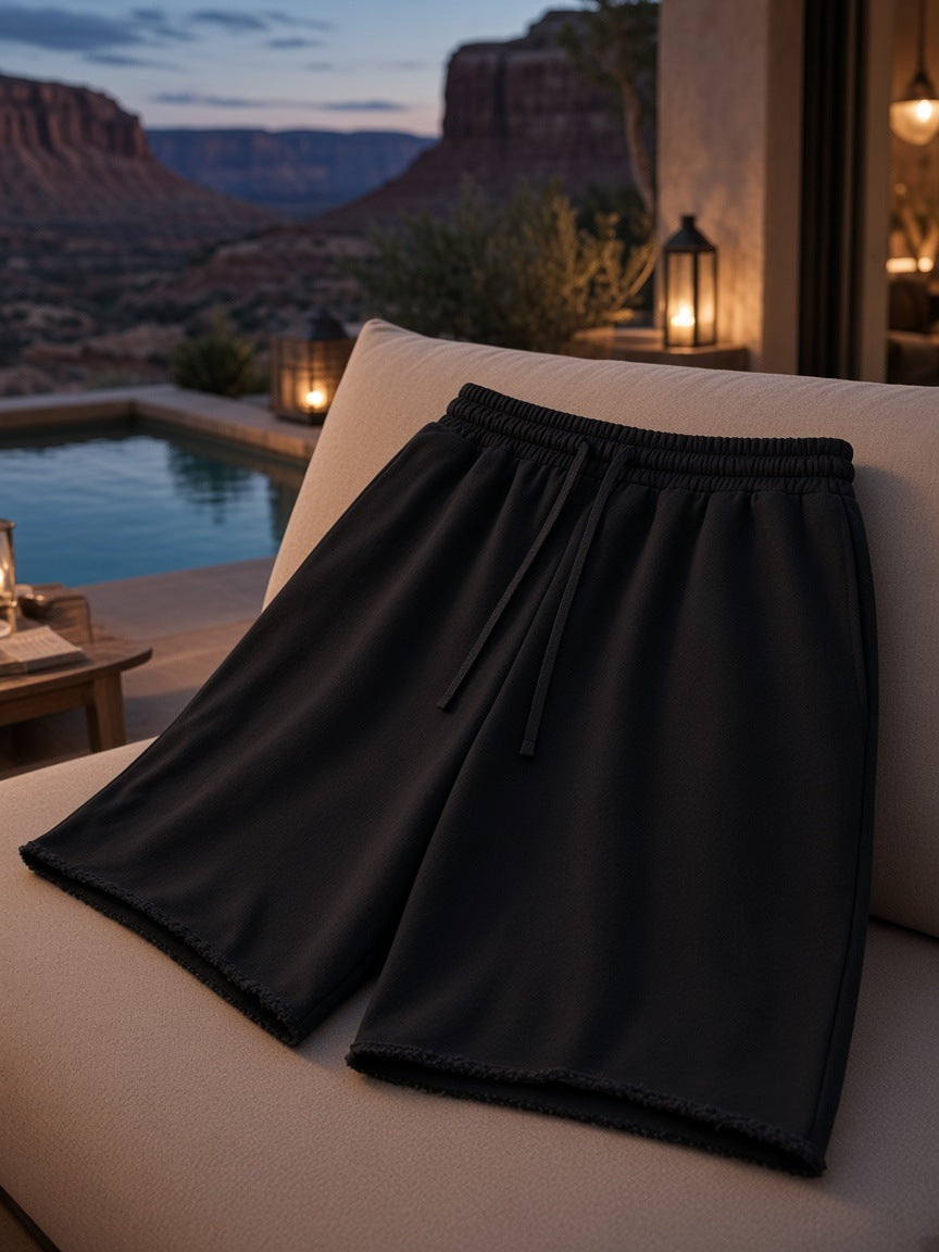 Marcel Afters Loose Raw Edge Shorts in Black, laid flat, outdoor