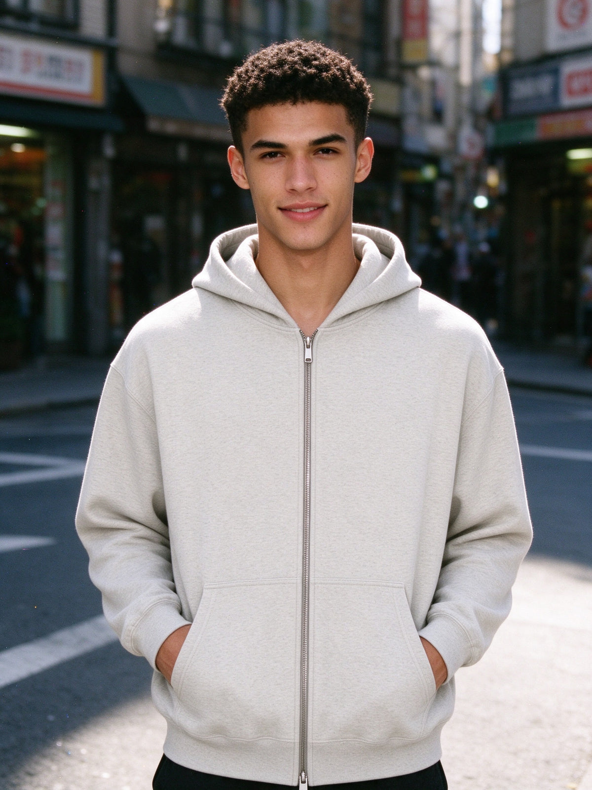 Man wearing the Marcel Afters Men's Heavyweight Full Zip Hoodie, Light Tones in Oat Gray, full-length editorial photograph