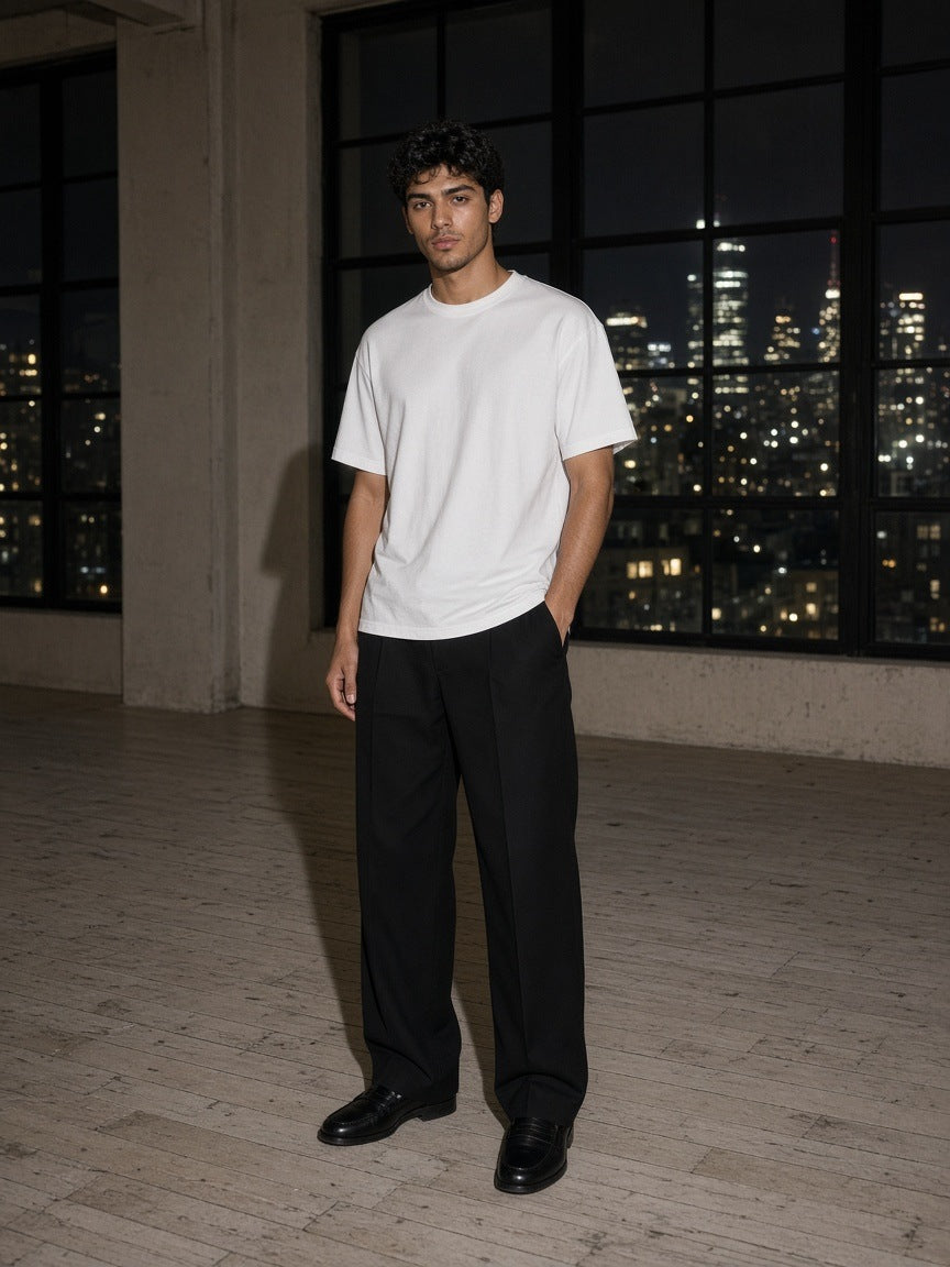 Marcel Afters Men's Oversized T-Shirt in White, worn by a man, standing in a dark loft above the city lights