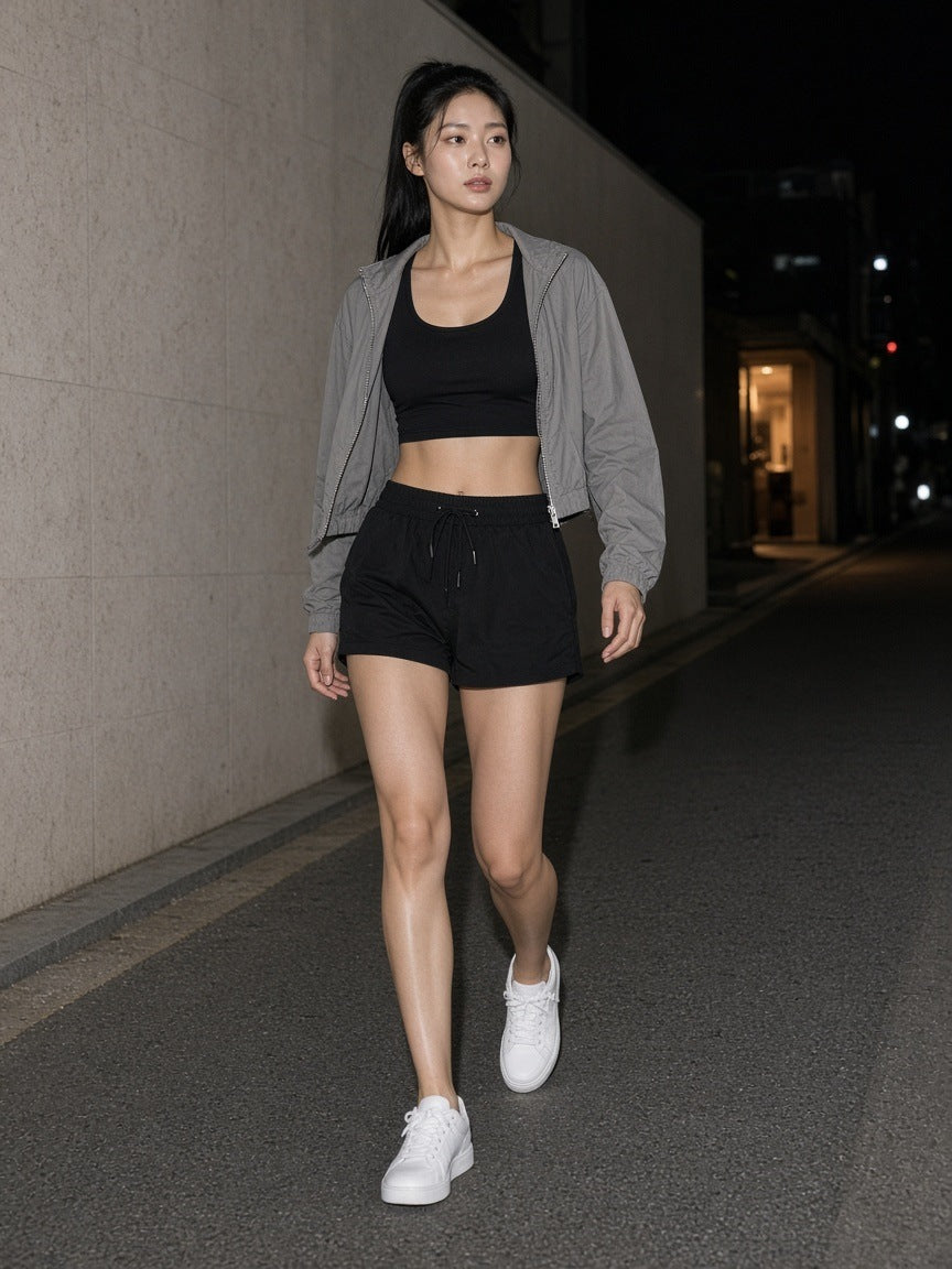 Marcel Afters Mesh-Lined Quick-Dry Performance Shorts in Black, worn by a woman, alley