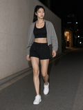 Marcel Afters Mesh-Lined Quick-Dry Performance Shorts in Black, worn by a woman, alley