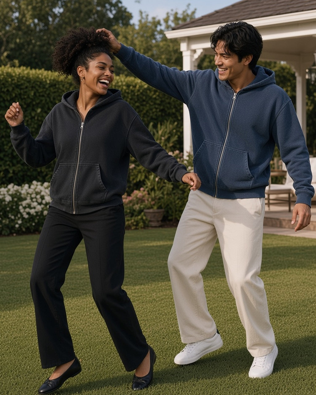 Two people in the Mineral Wash Boxy Full Zip Hoodie in Black and Navy Blue, dancing on a club lawn at golden hour