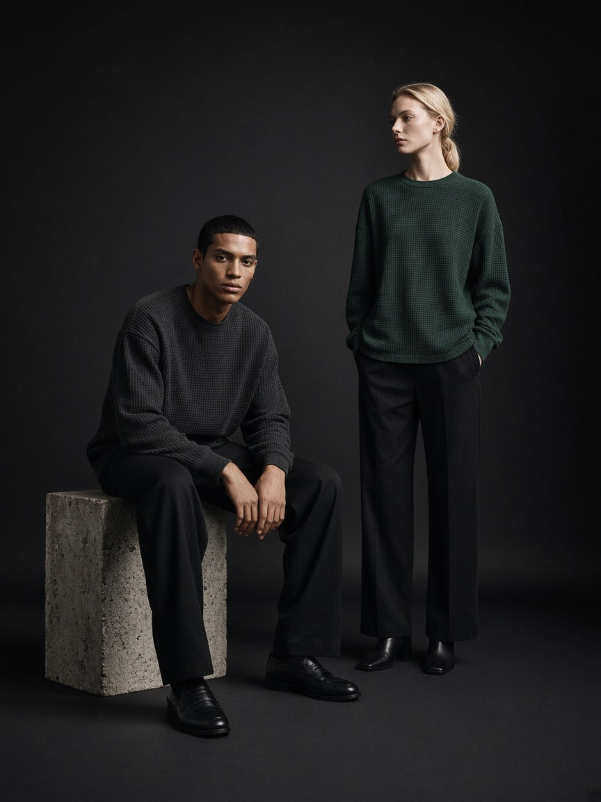 Marcel Afters Mineral Wash Waffle Oversized T-Shirt — Dark in Black, worn by a man and a woman, posed in a dark studio, he seated on a stone block and she standing in green