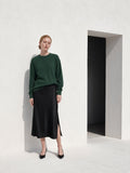 Marcel Afters Mineral Wash Waffle Oversized T-Shirt — Dark in Blackish Green, worn by a woman, standing against a white wall in a long black skirt