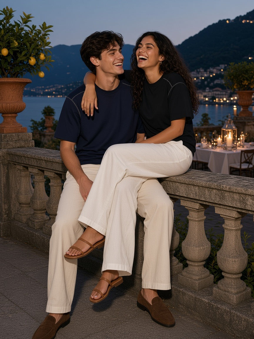 Marcel Afters Oversized Contrast-Stitched Cotton Tee in Navy Blue, worn by a man and a woman, seated together on a lakeside balustrade at dusk