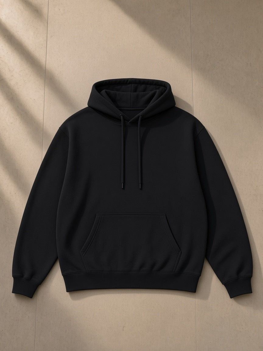 Unisex oversized drop shoulder hoodie in Black, laid flat on pale limestone, front view