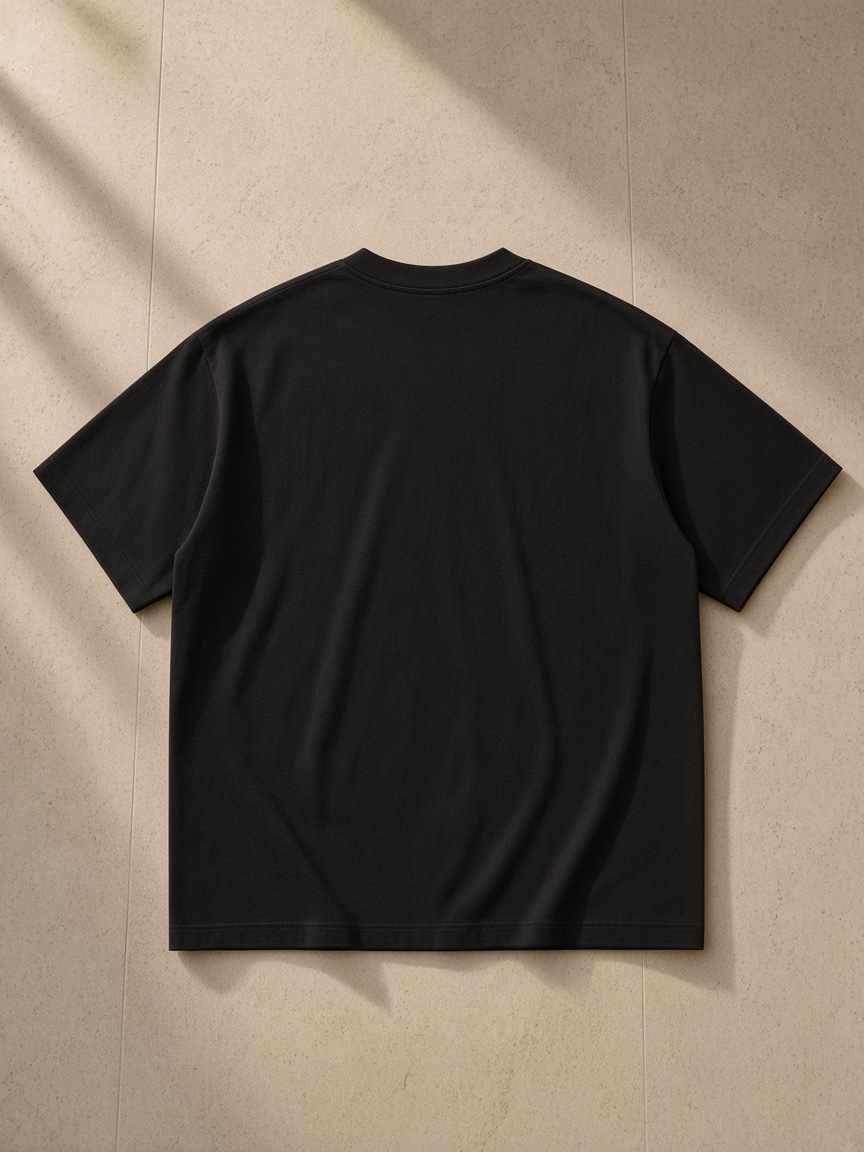 Men's Oversized T-Shirt in Black, laid flat on pale limestone, back view